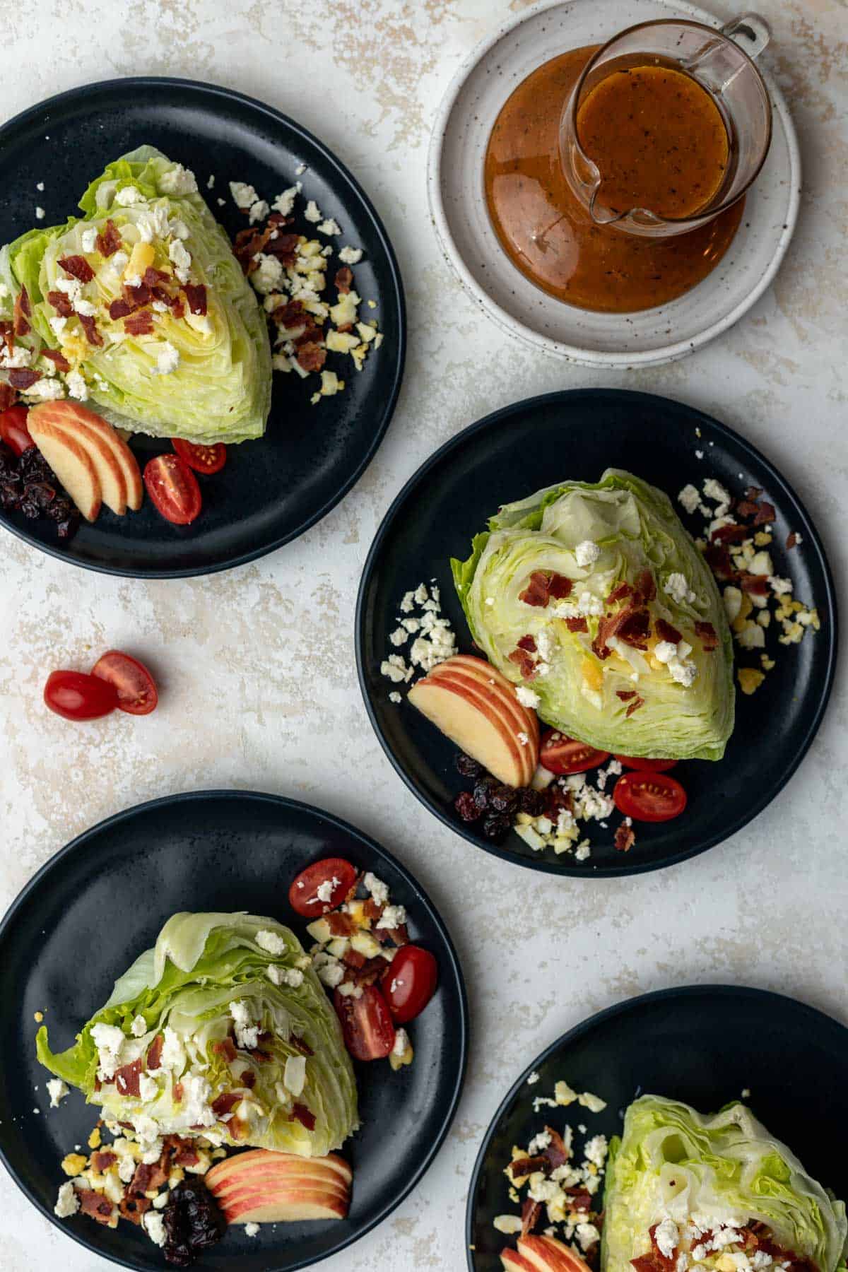 Assembled fall cobb wedge salads on 4 blue plates with a pitcher of pumpkin dressing next to them.