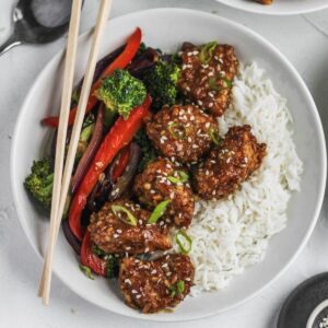 Air fryer almond chicken on rice with a side of stir fried vegetables.