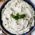 Mashed potatoes in a serving bowl topped with chives.
