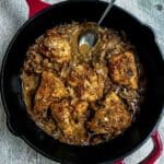 Chicken marsala in a red cast iron skillet with a serving spoon.