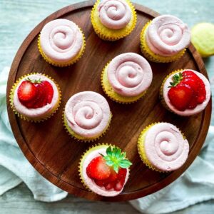 Strawberry buttercream on almond cupcakes with a strawberry topping.