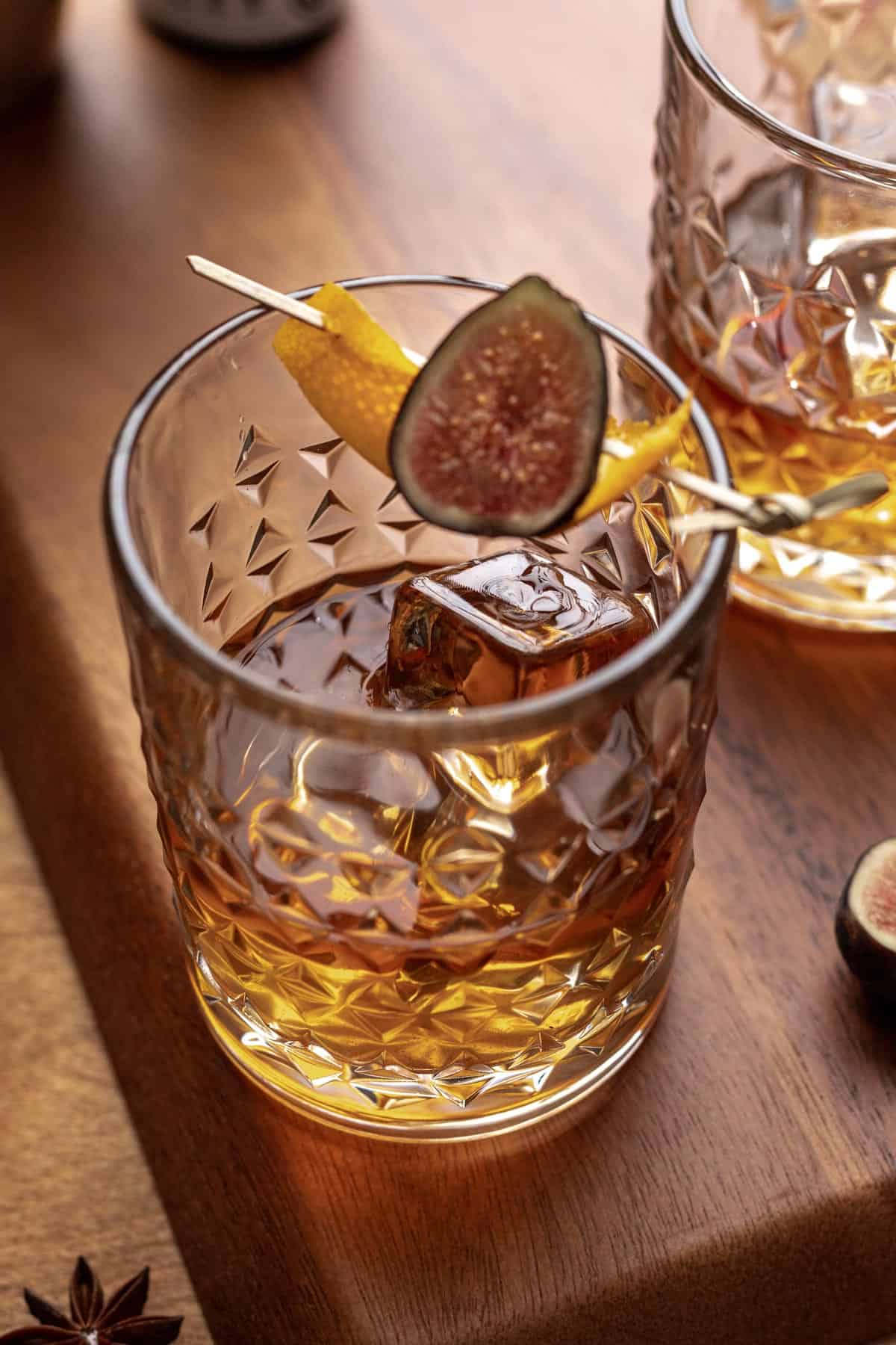 A vanilla fig old fashioned garnished with an orange peel and fresh fig.