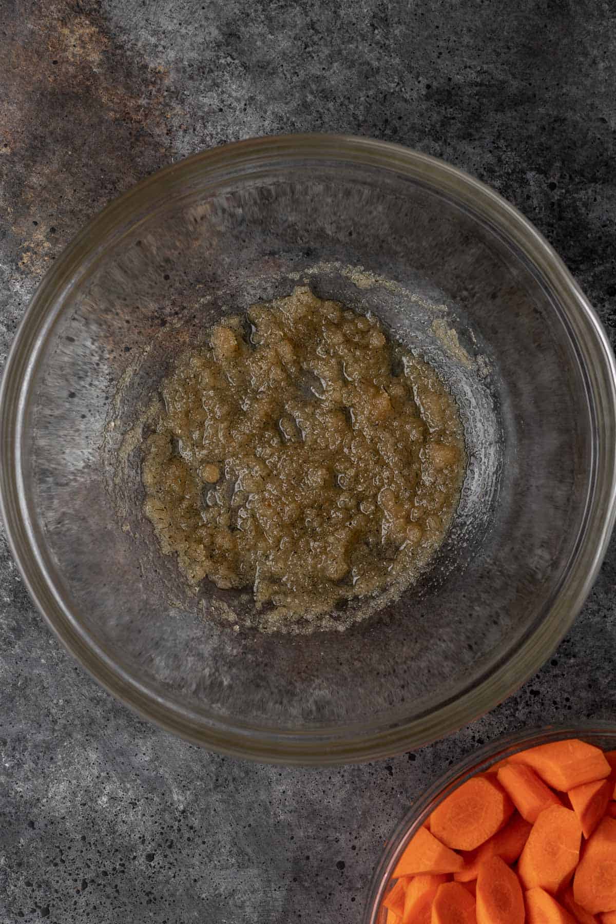 Brown sugar mixed with olive oil and seasonings in a glass mixing bowl.