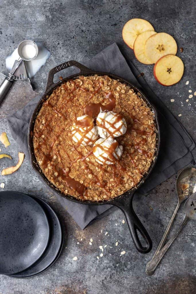 Bourbon caramel apple crisp topped with 3 scoops of vanilla ice cream and a drizzle of caramel sauce.