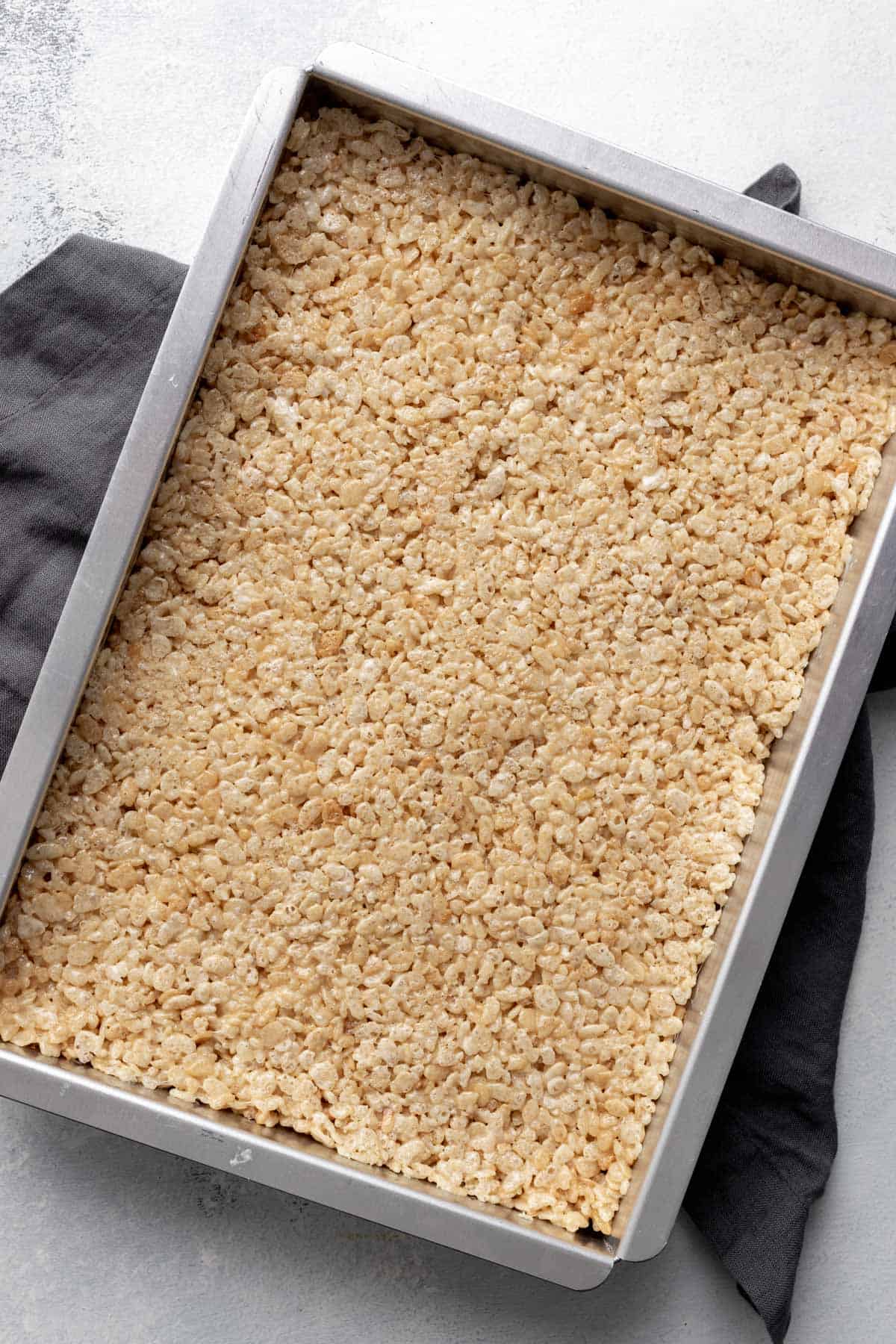 Gooey rice krispie treats spread out in a pan before cutting.