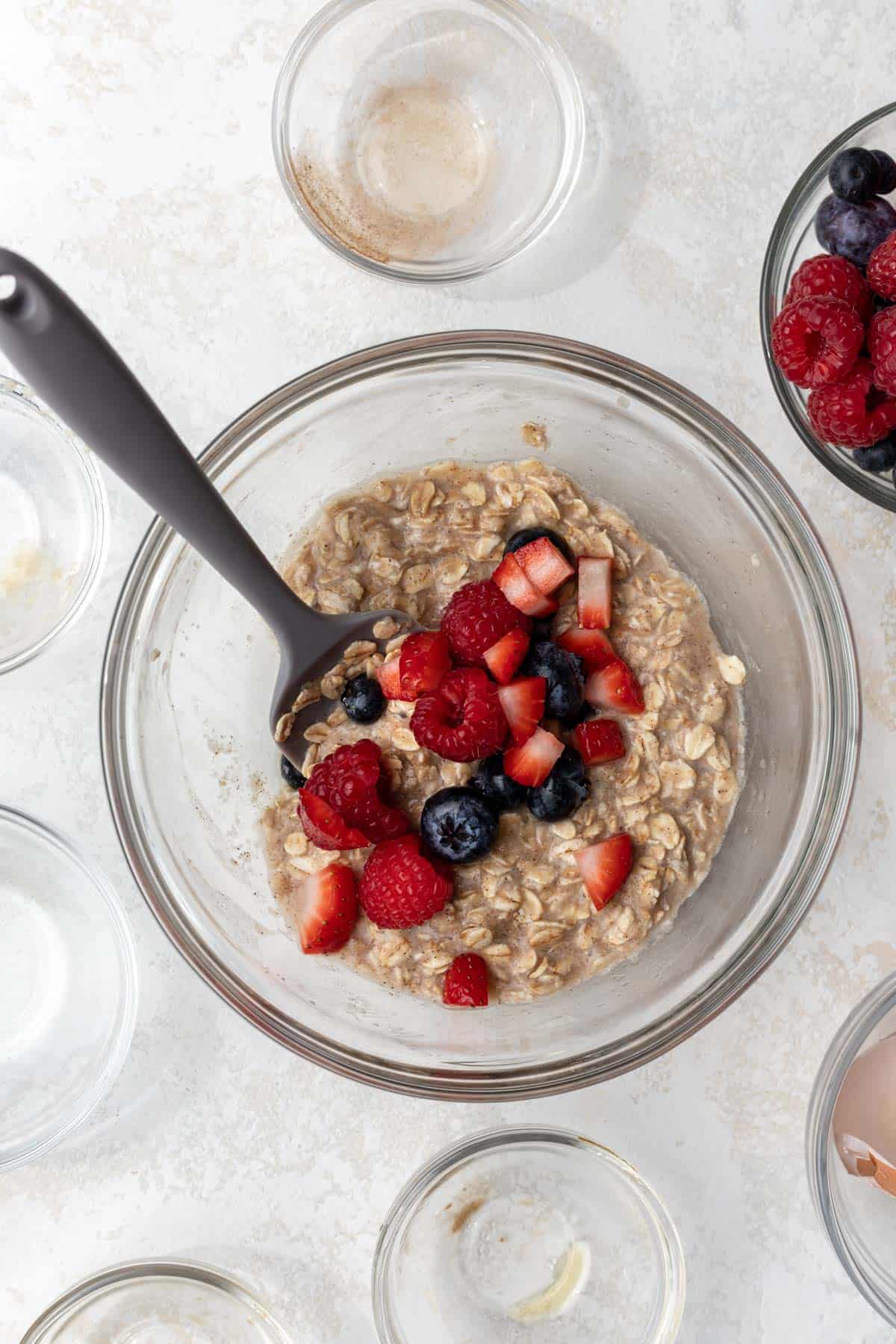 Baked oat batter with berries in a mixing bowl.