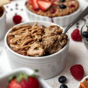 Peanut butter banana baked oats in a white ramekin with a spoon.