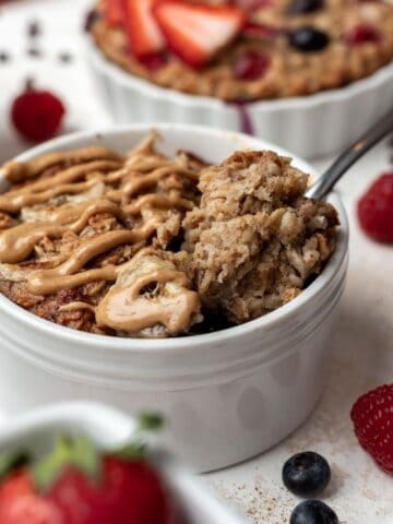 Peanut butter banana baked oats in a white ramekin with a spoon.