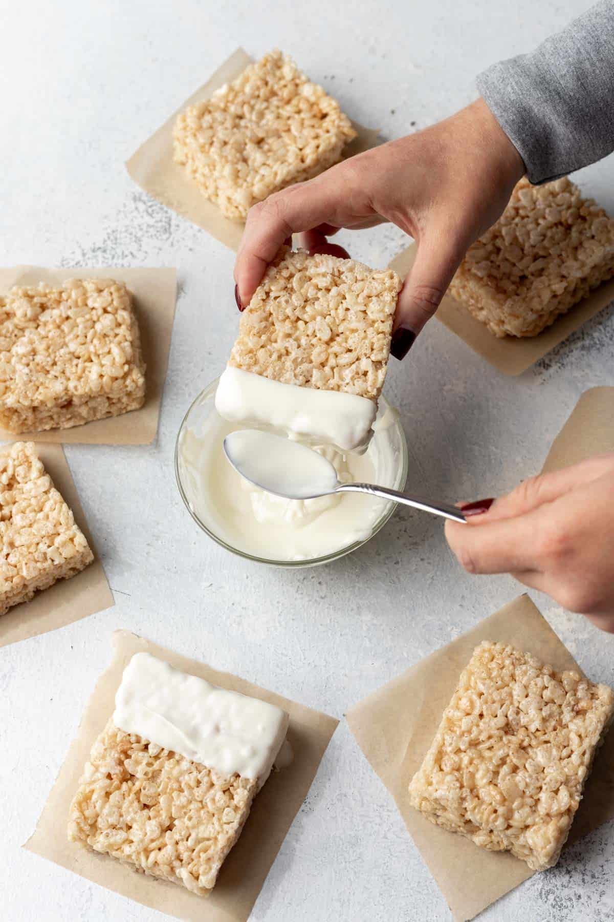 Top of a rice krispie treat dipping in melted white chocolate.