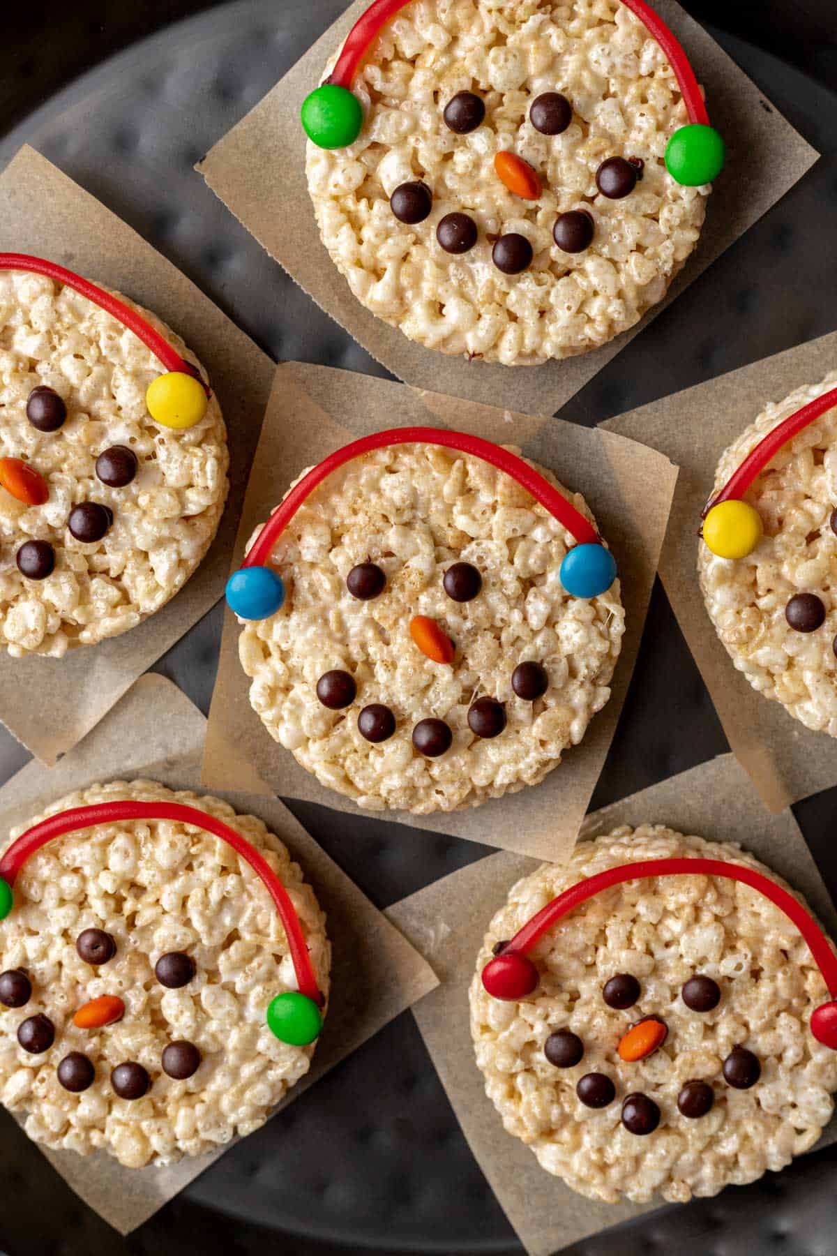 Snowman rice krispie treats with an orange candy nose and candy string earmuffs.