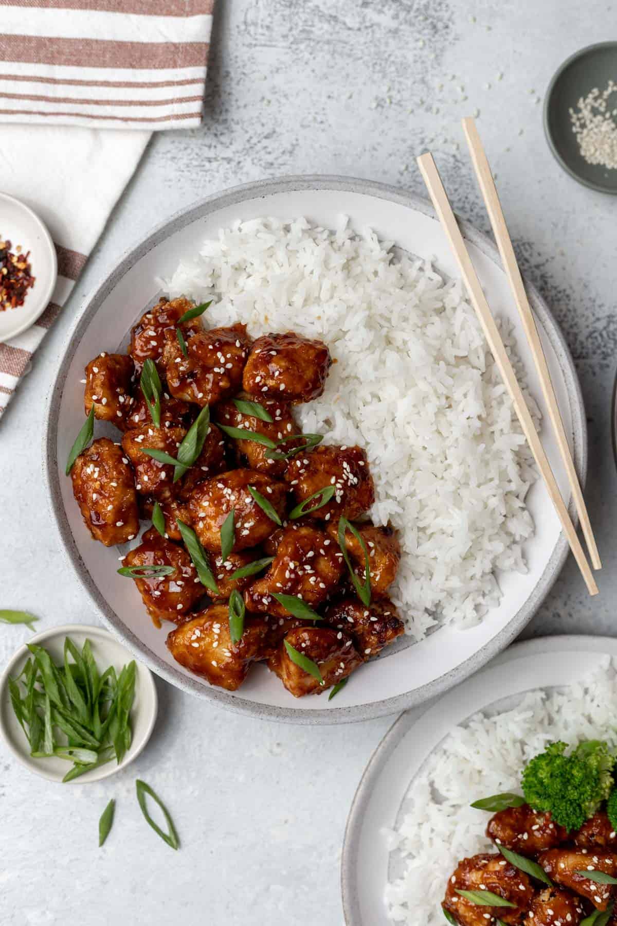 Air fryer general tso's chicken in a bowl with white rice and chopsticks.