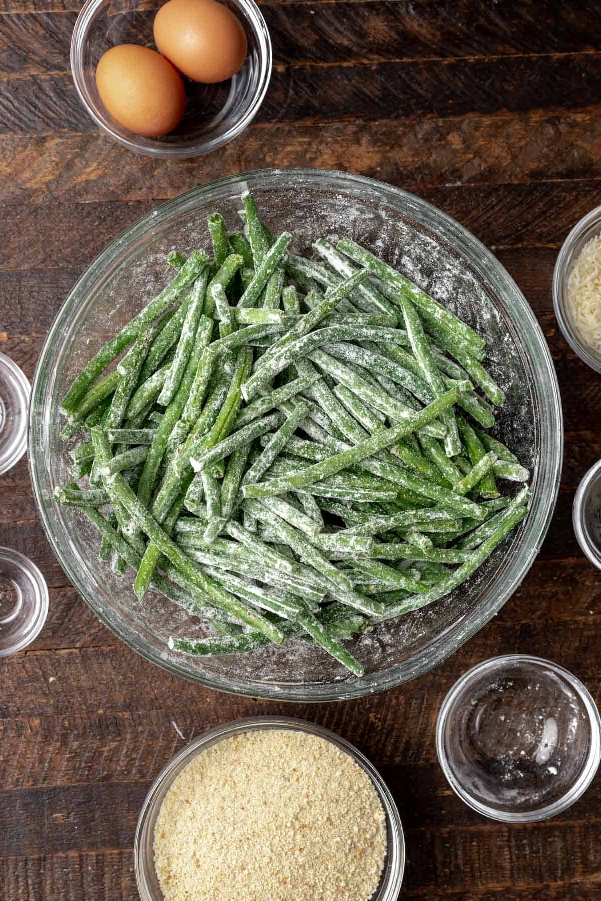 Green beans coated in flour in a large mixing bowl.