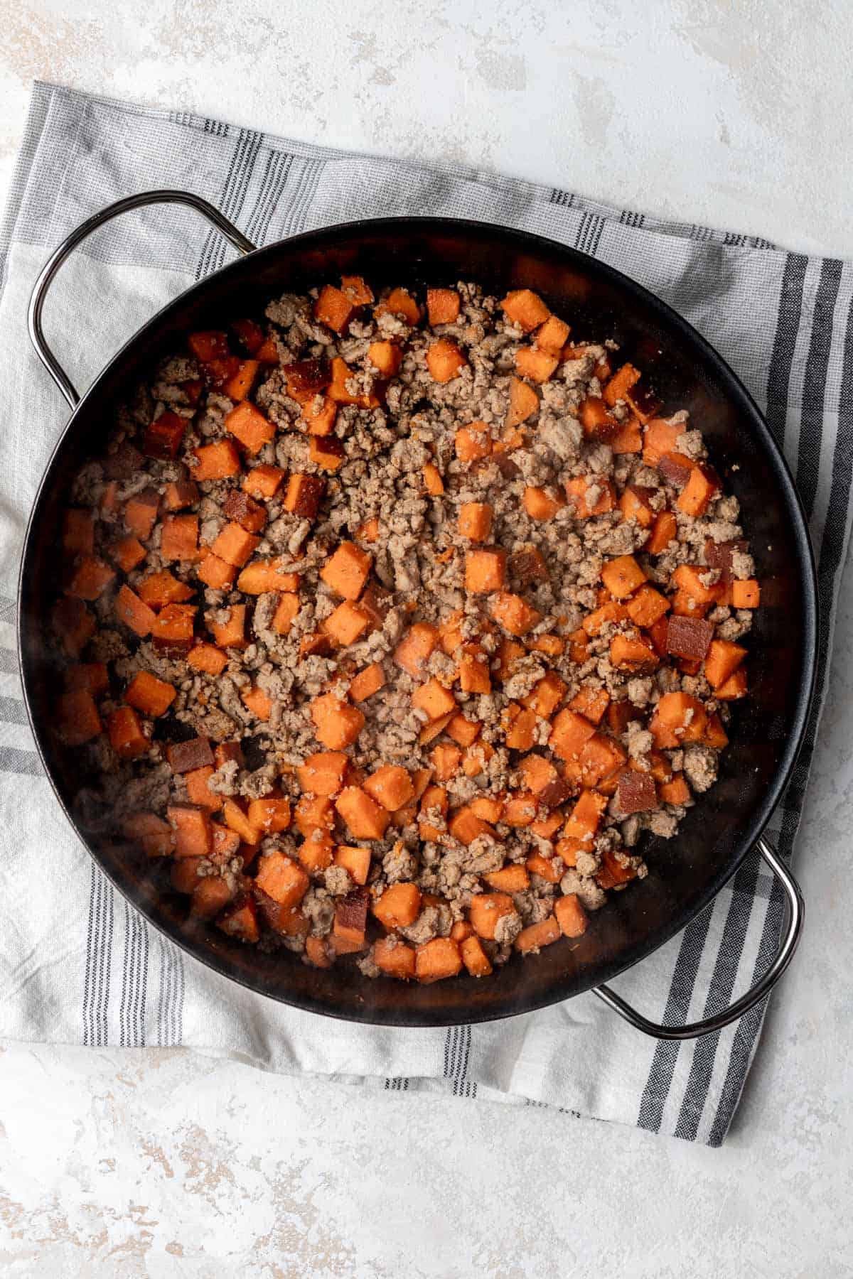 Cooked sweet potatoes with ground turkey in a large skillet.