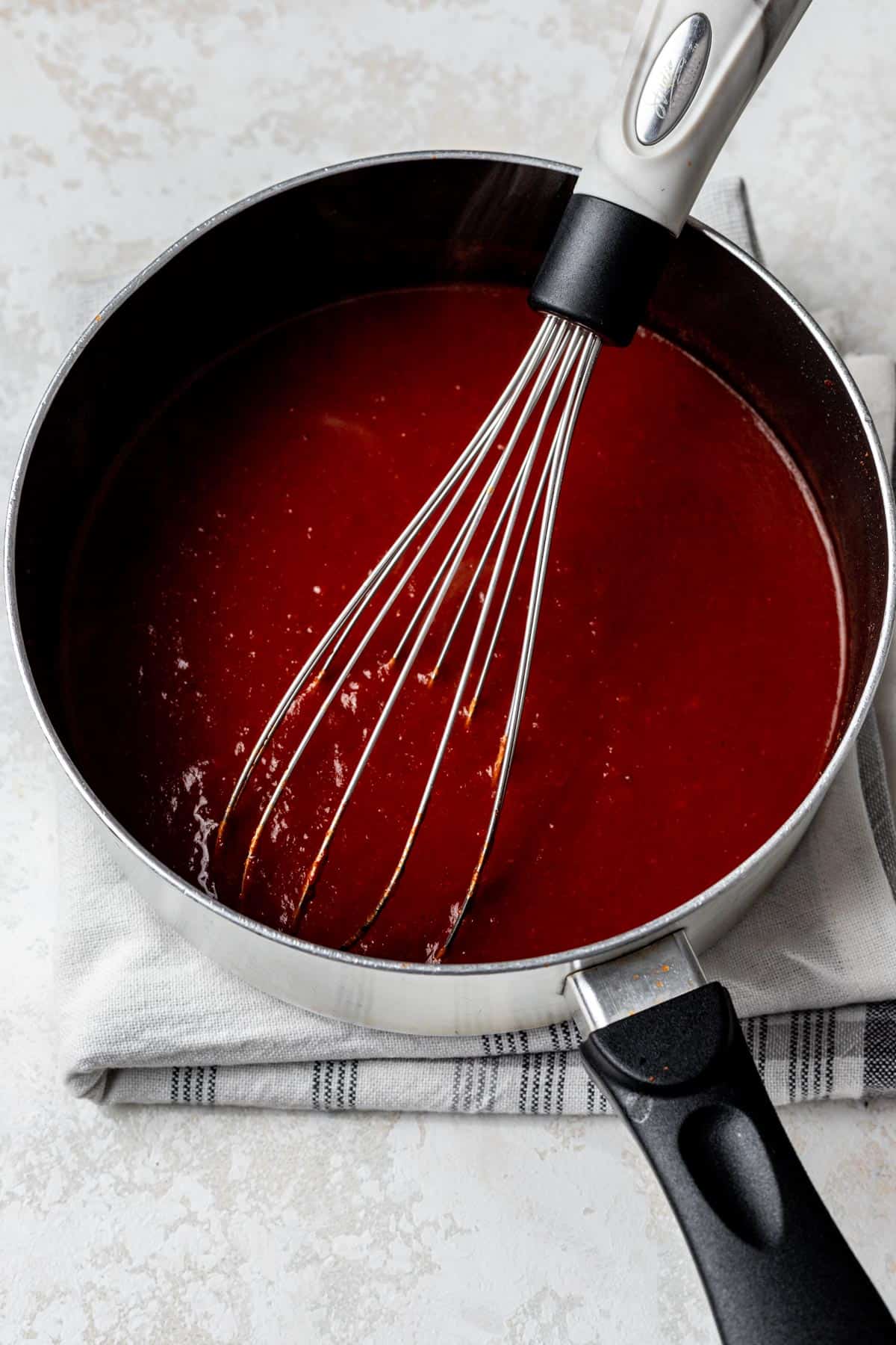 Enchilada sauce whisked in a saucepan.