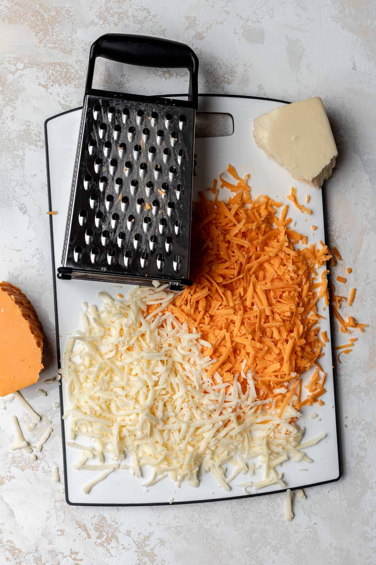 Shredded cheese on a cutting board with a box grater.