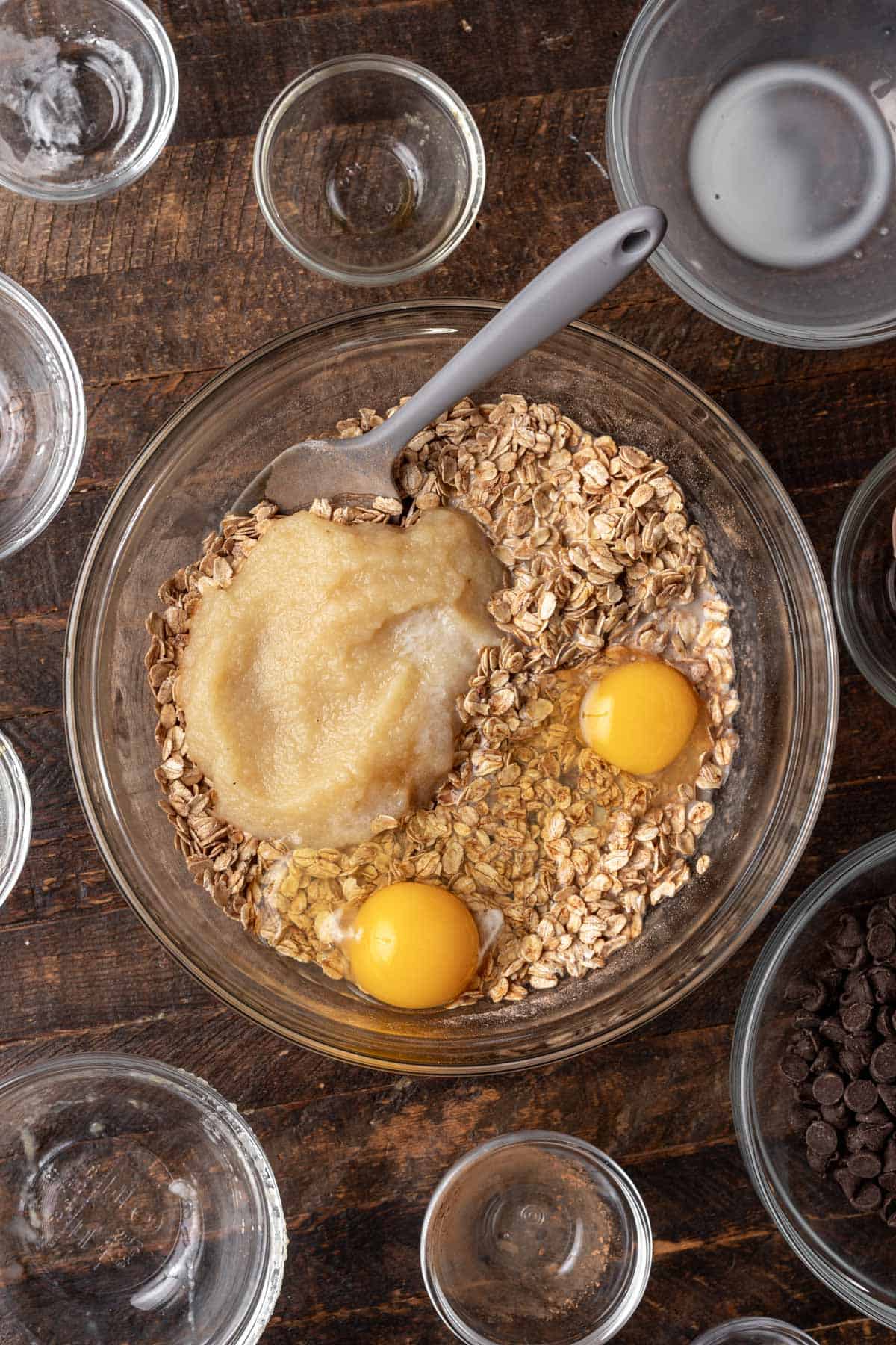 Dry ingredients in a bowl with applesauce, eggs, melted coconut oil, and other wet ingredients.