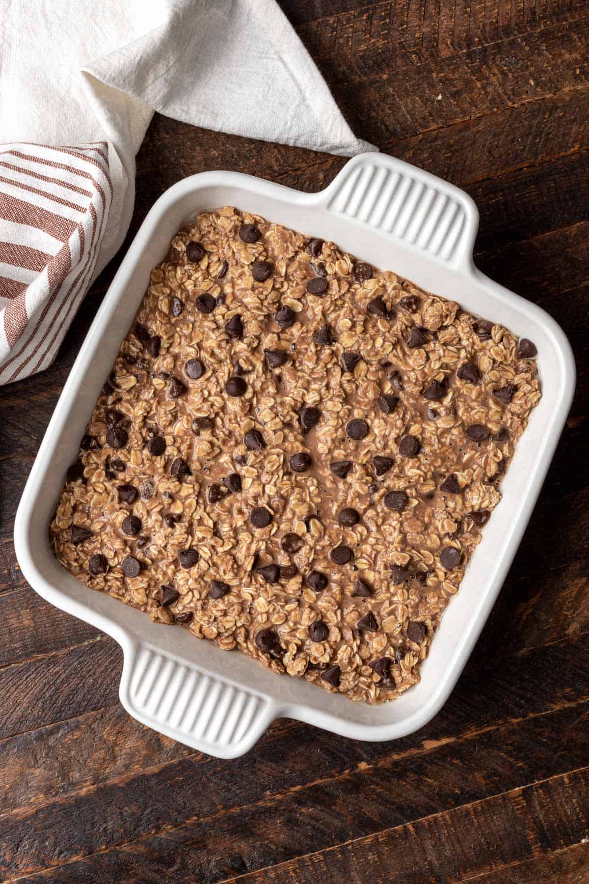 Raw baked oatmeal in a white baking dish before going in the oven.