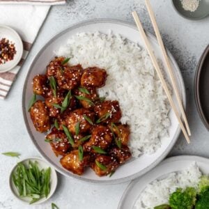 Air fryer general tso's chicken in a bowl with white rice and chopsticks.