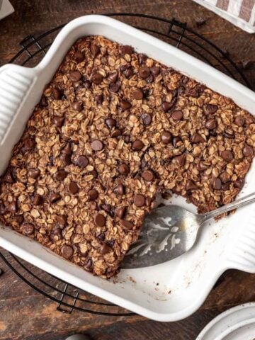 Chocolate baked oats in a white ceramic baking dish with a serving spatula.
