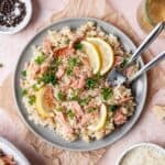 Risotto topped with smoked salmon, sliced lemons, and fresh parsley.