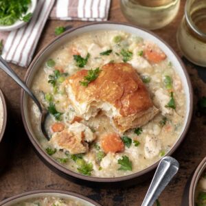 Instant pot chicken pot pie topped with a puff pastry biscuit and garnished with fresh parsley.