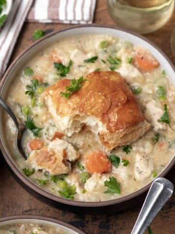 Instant pot chicken pot pie topped with a puff pastry biscuit and garnished with fresh parsley.