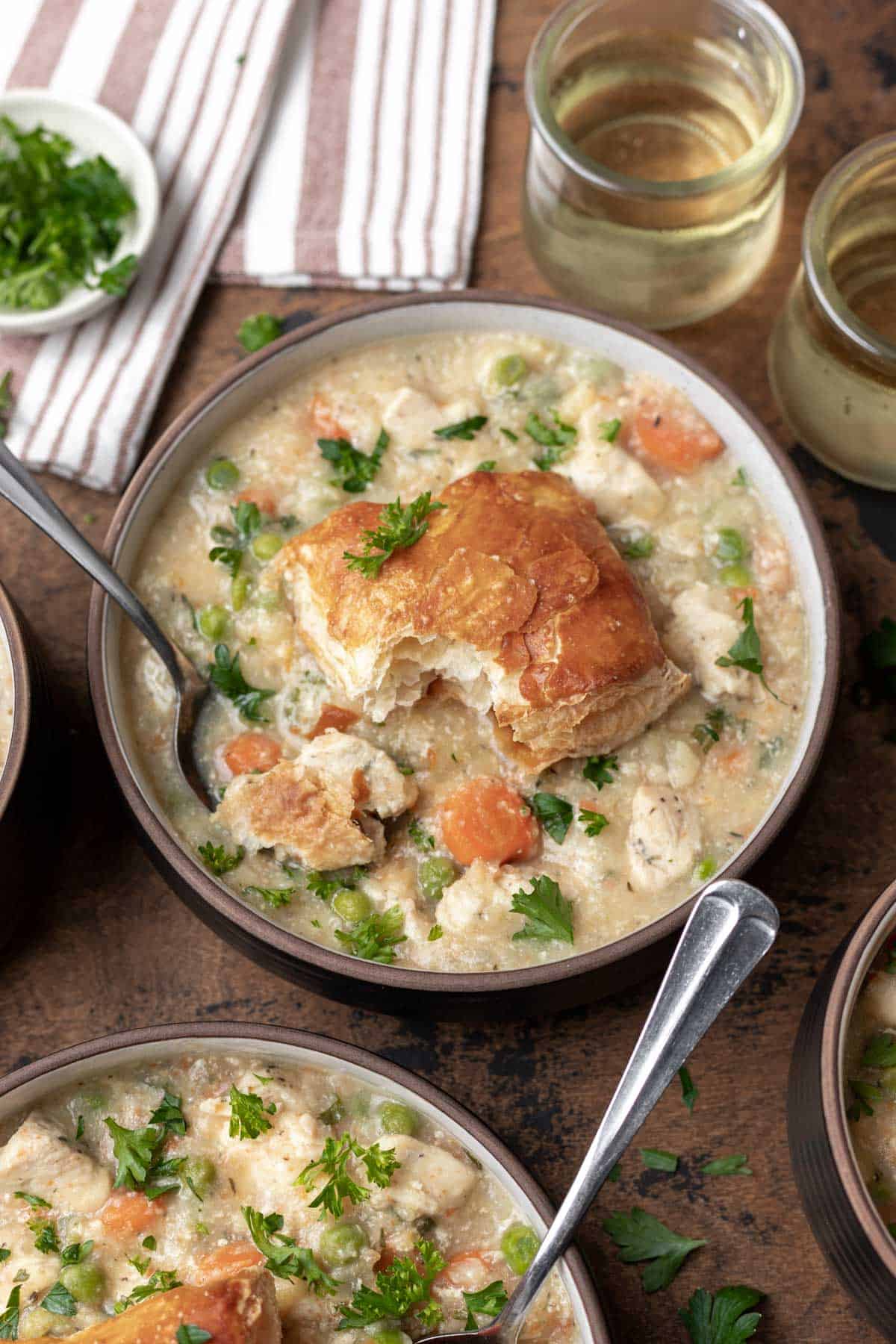 Instant pot chicken pot pie topped with a puff pastry biscuit and garnished with fresh parsley.