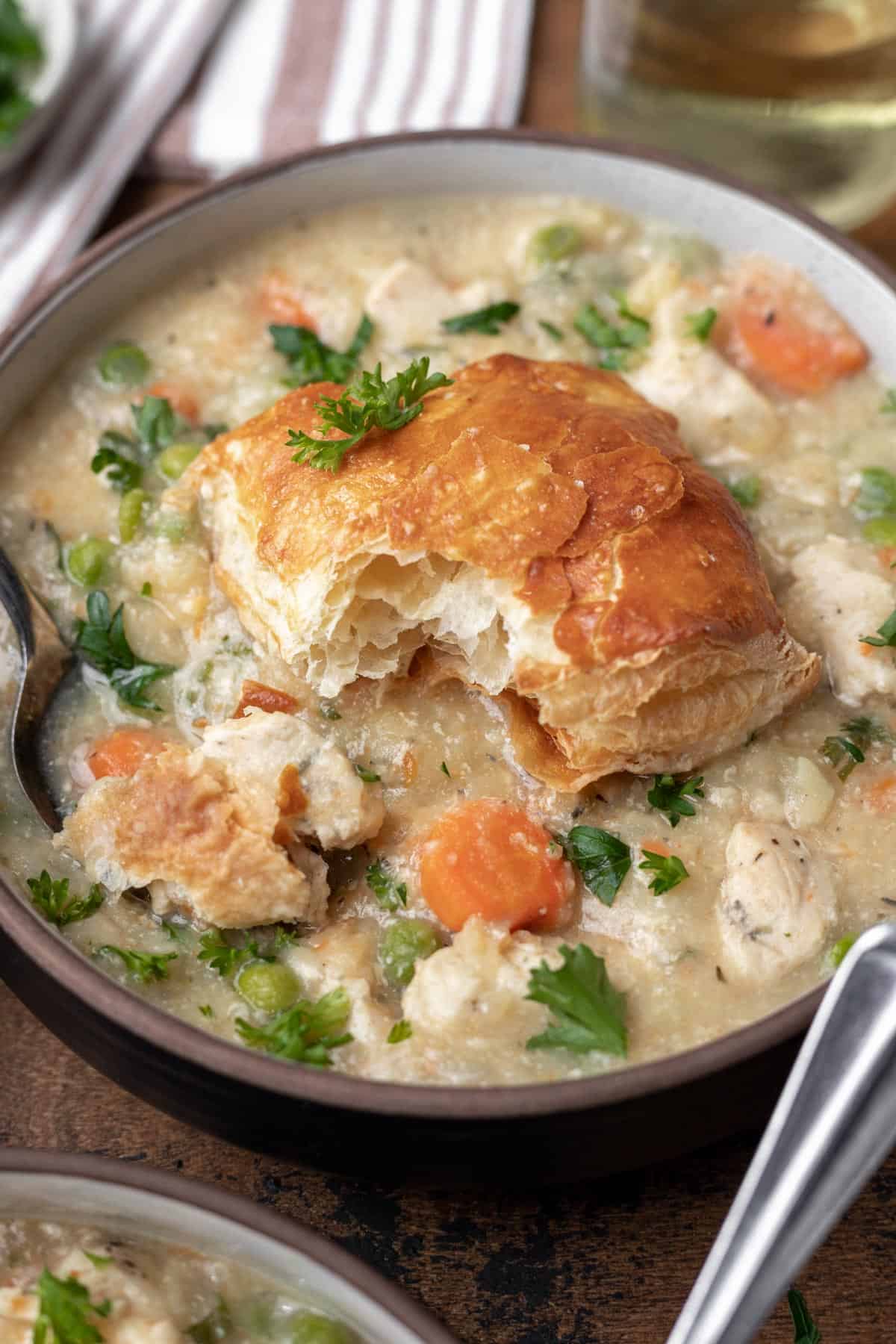 Instant pot chicken pot pie topped with a flakey puff pastry biscuit and a spoon.