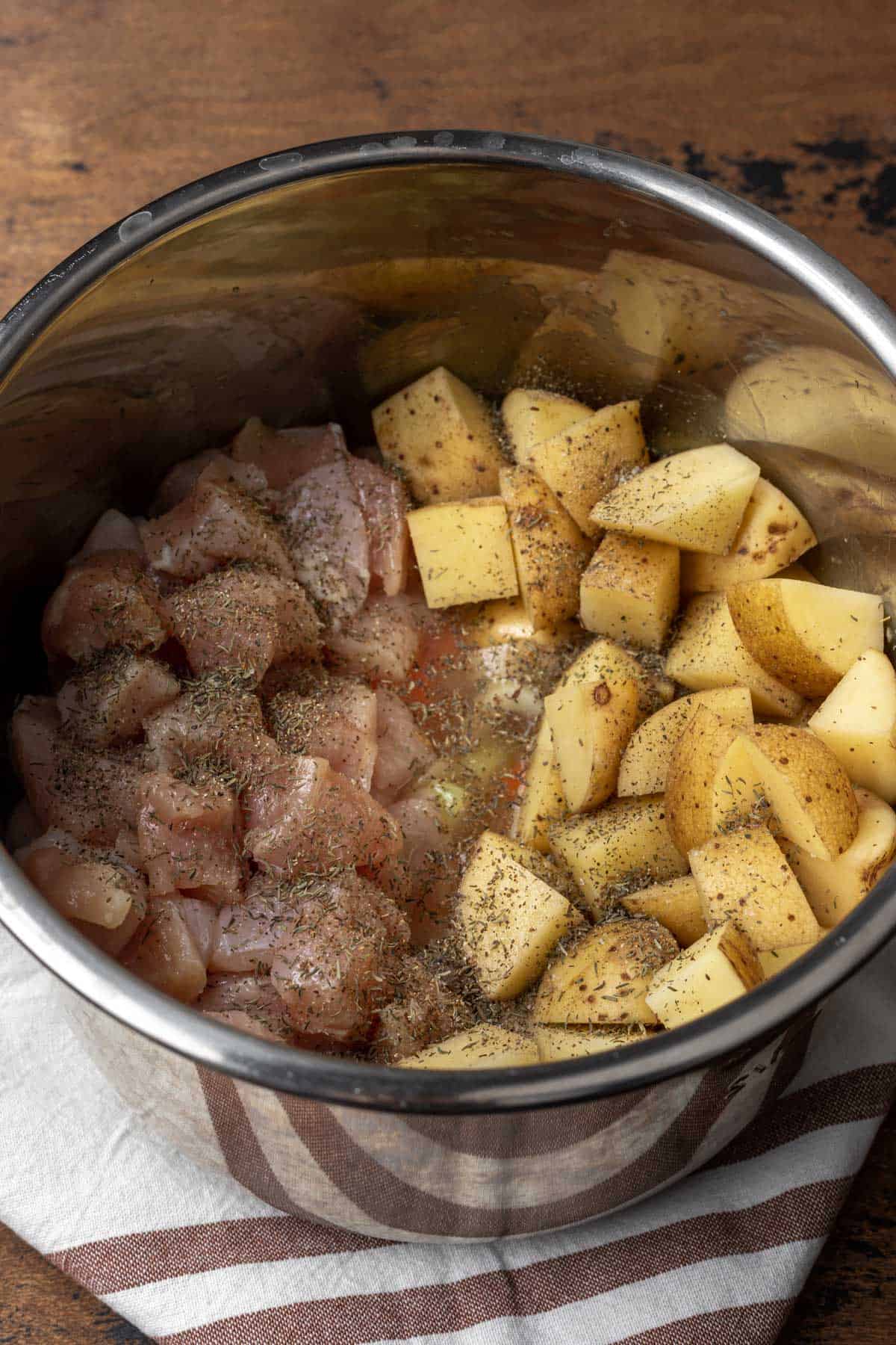 Cubed chicken, potatoes, broth, and seasoning added to the instant pot.