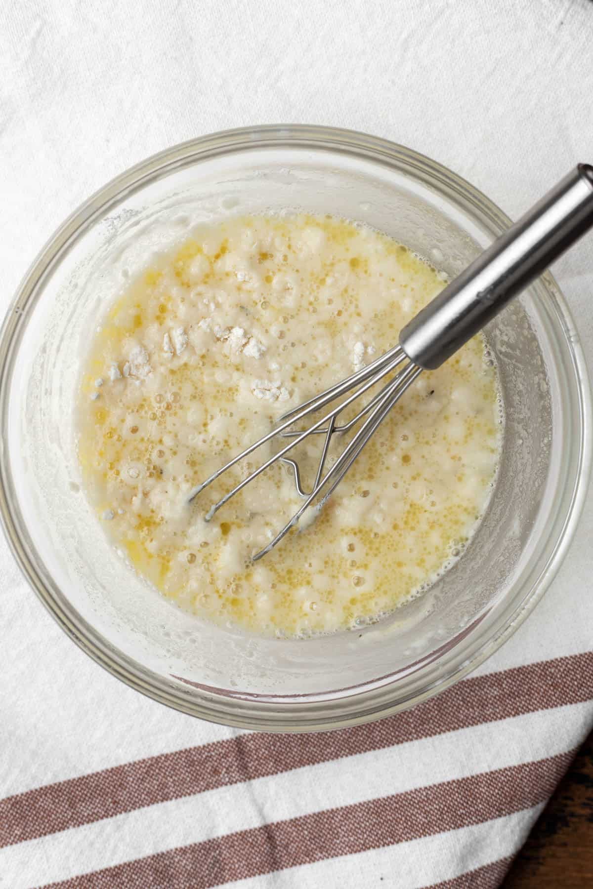 Broth in a mixing bowl whisked with flour.