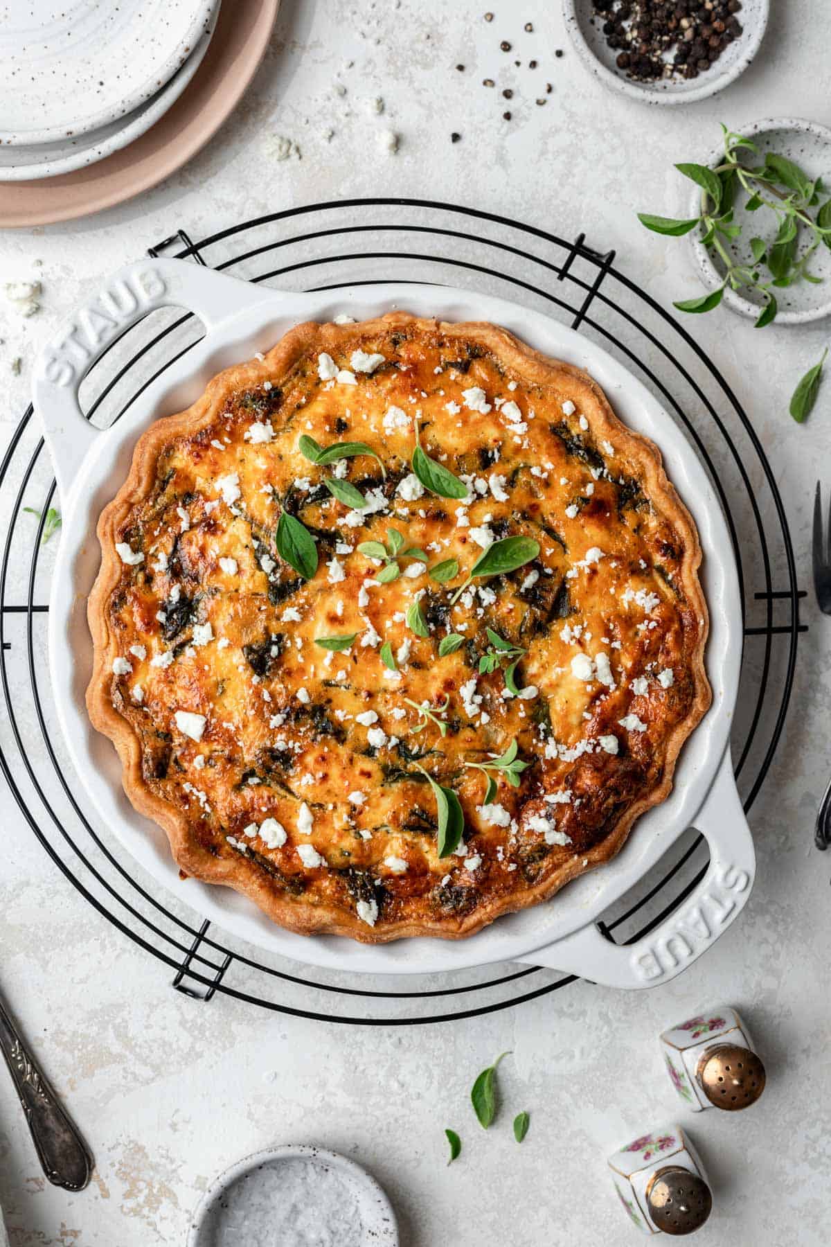 Mediterranean sun-dried tomato quiche in a white baking dish on a cooling rack.