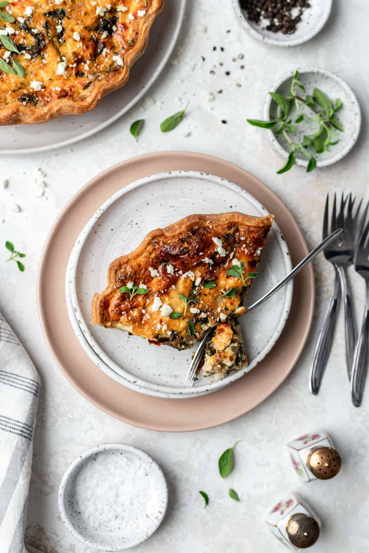 A slice of sun-dried tomato quiche with a fork cutting a small piece.