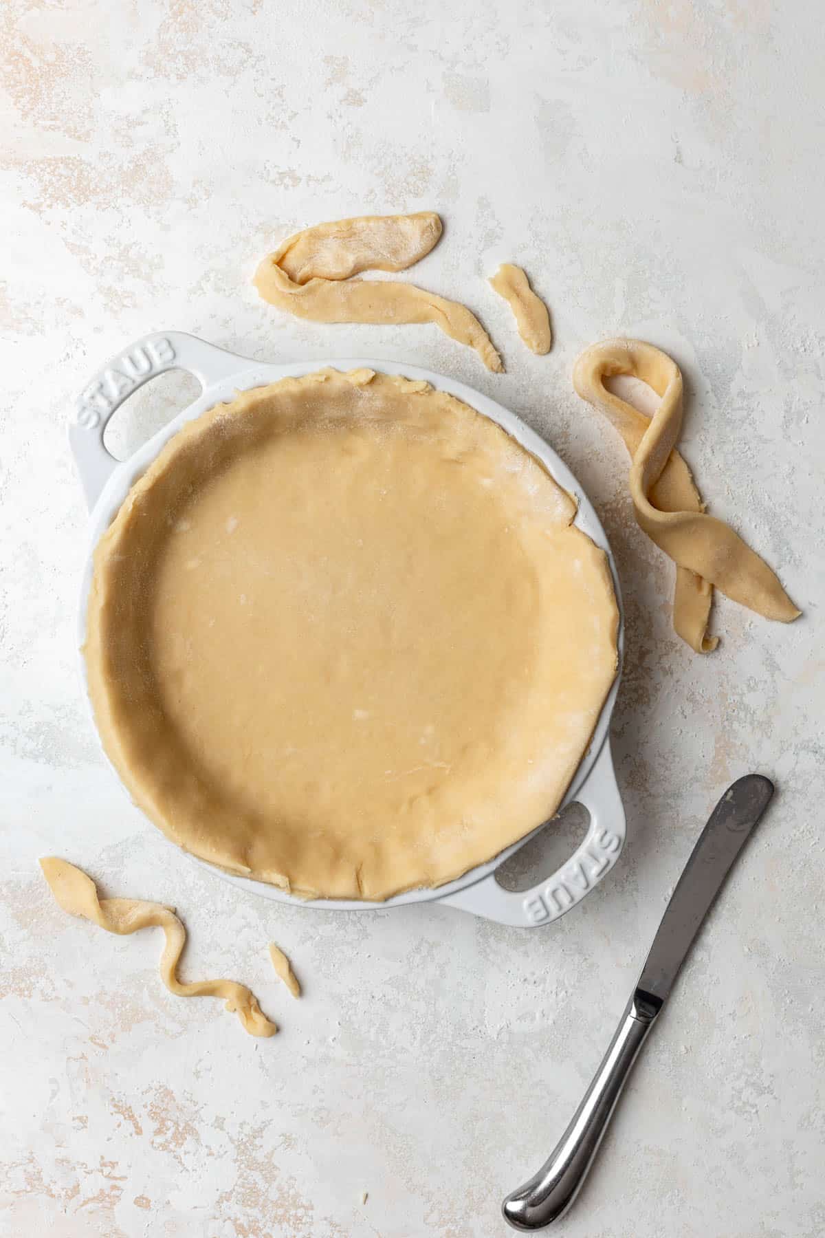 Quiche dough in a pie pan with excess cut off.