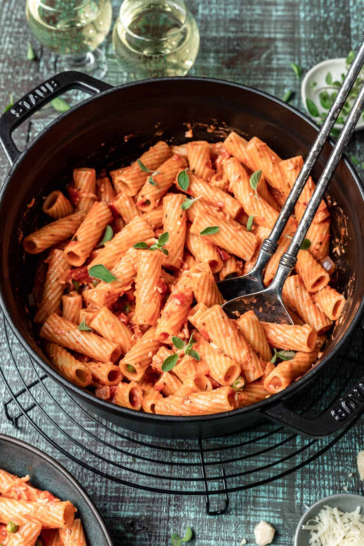 Pink sauce pasta in a black pot with two large serving spoons.