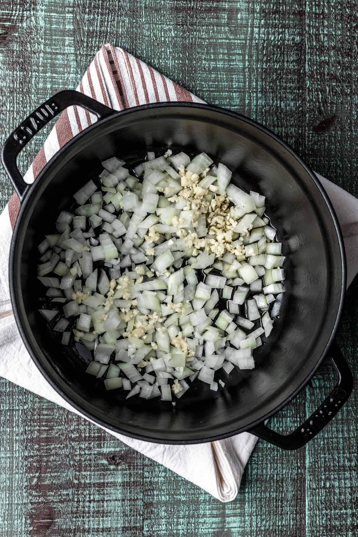 Onions and garlic sautéed in a large black pot.