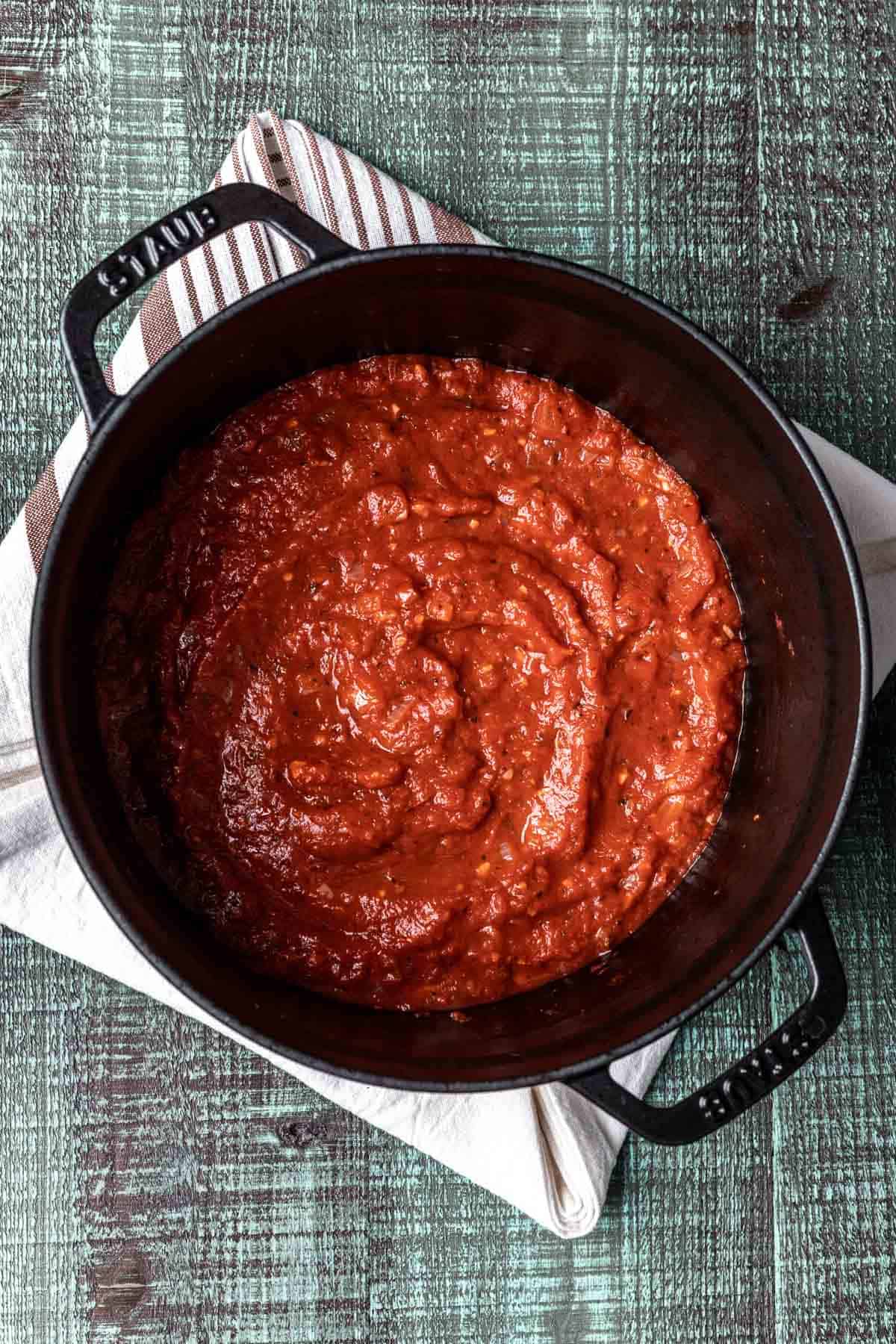 Thickened tomato sauce in a black pot.