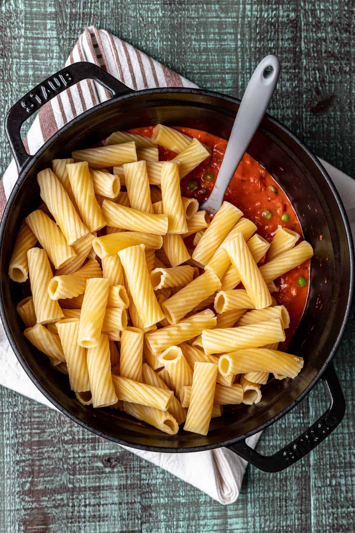 Pasta mixed into pink sauce in a large pot.