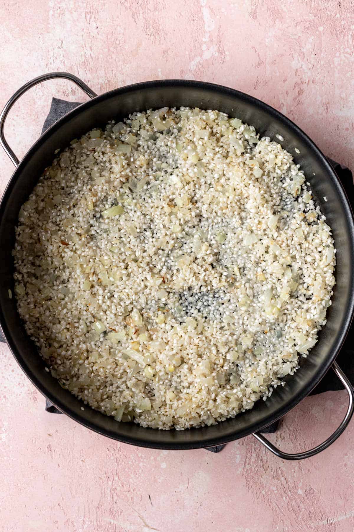 Arborio rice, onions, garlic, and white wine added to the skillet.