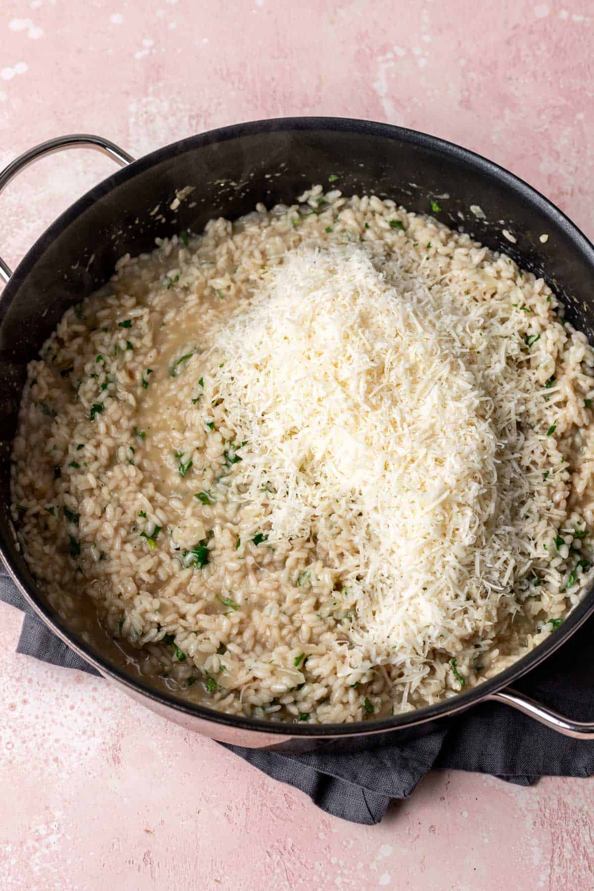 Cooked risotto topped with parmesan cheese before stirring.