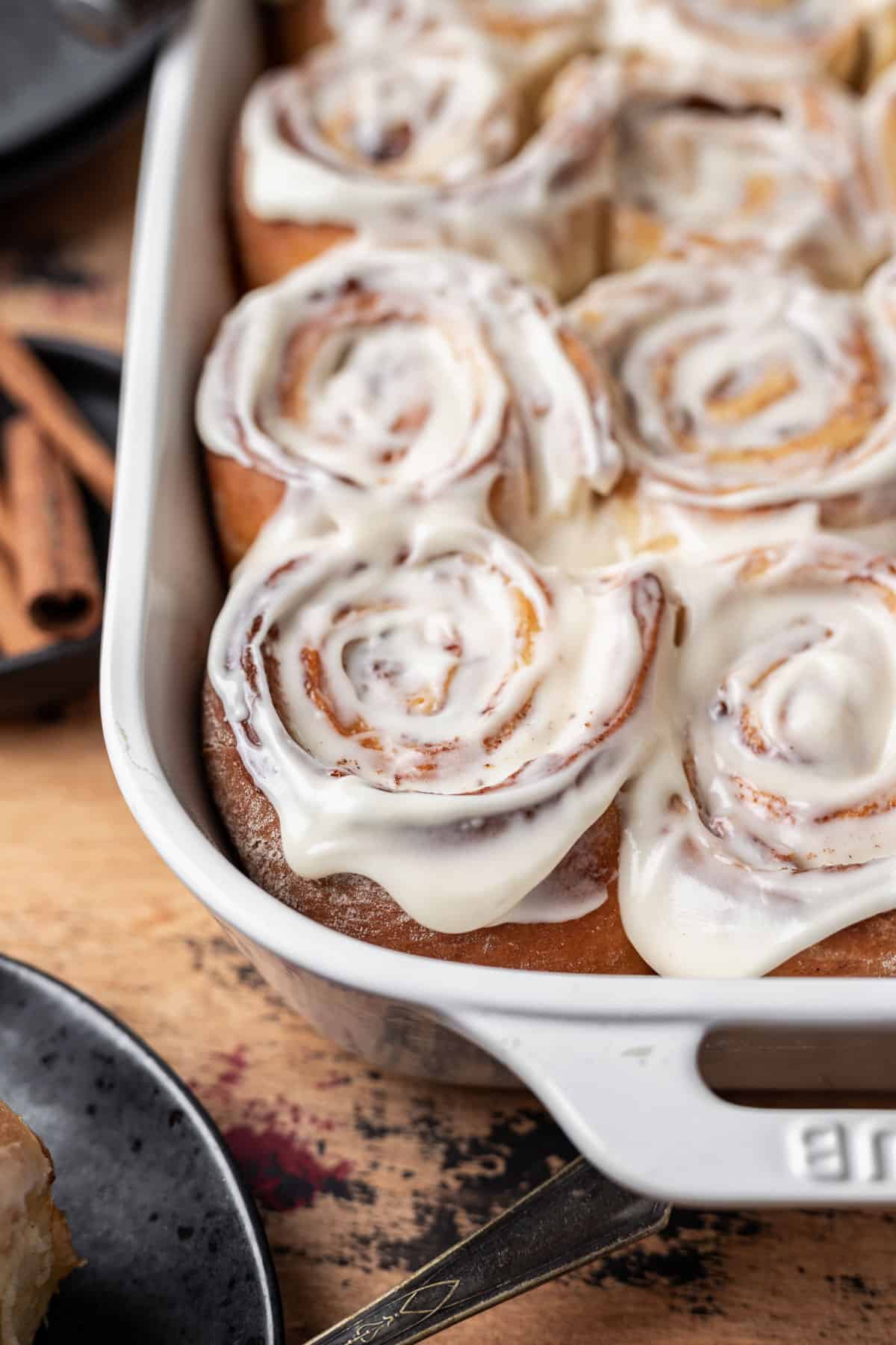 Cinnamon rolls with apple pie filling topped with a cream cheese icing in a baking dish.