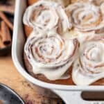 Cinnamon rolls with apple pie filling topped with a cream cheese icing in a baking dish.