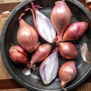 A bunch of shallots in a metal dish.