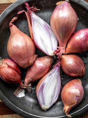 A bunch of shallots in a metal dish.