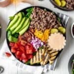 Loaded burger bowls topped with avocado, grilled pineapple, pickles, cheese, bacon, and tomatoes.