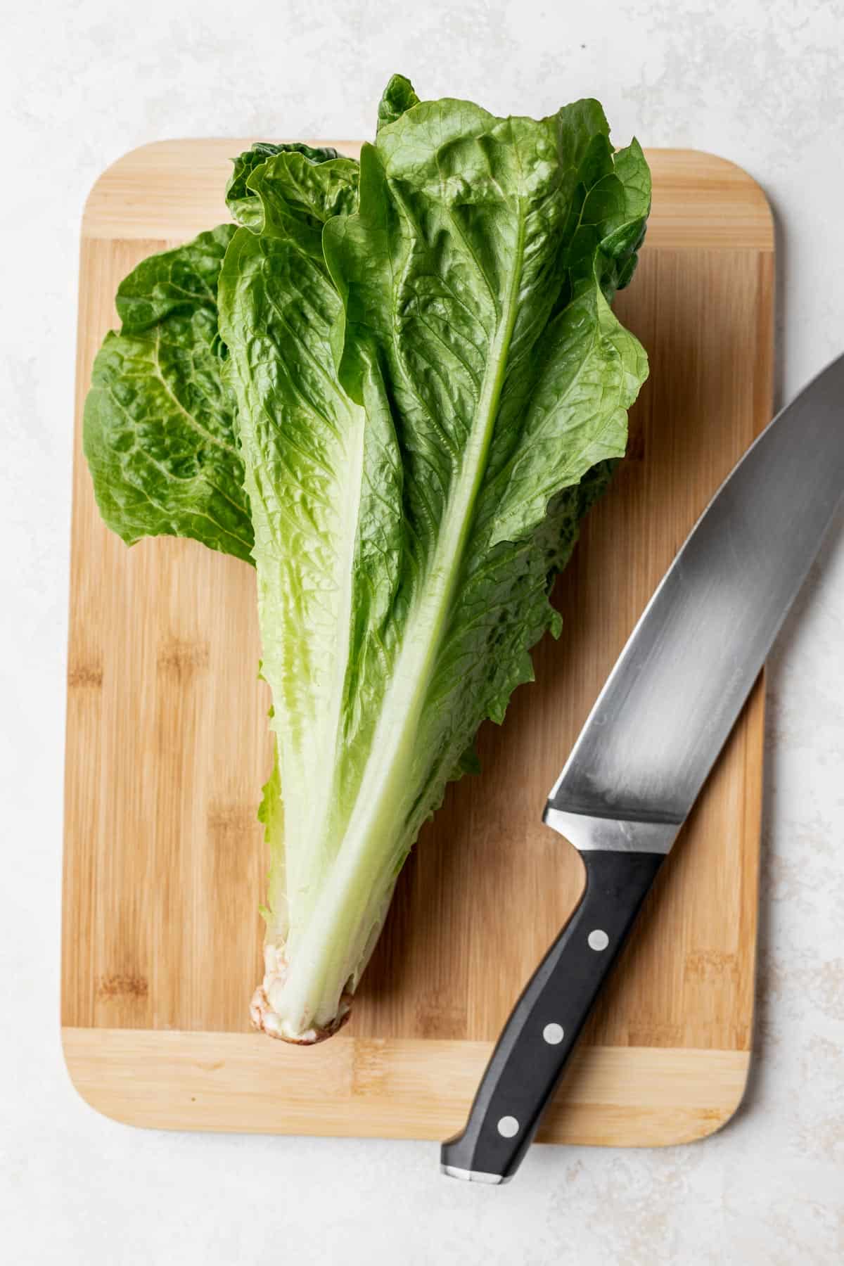 Romaine lettuce on a cutting board with a knife next to it.