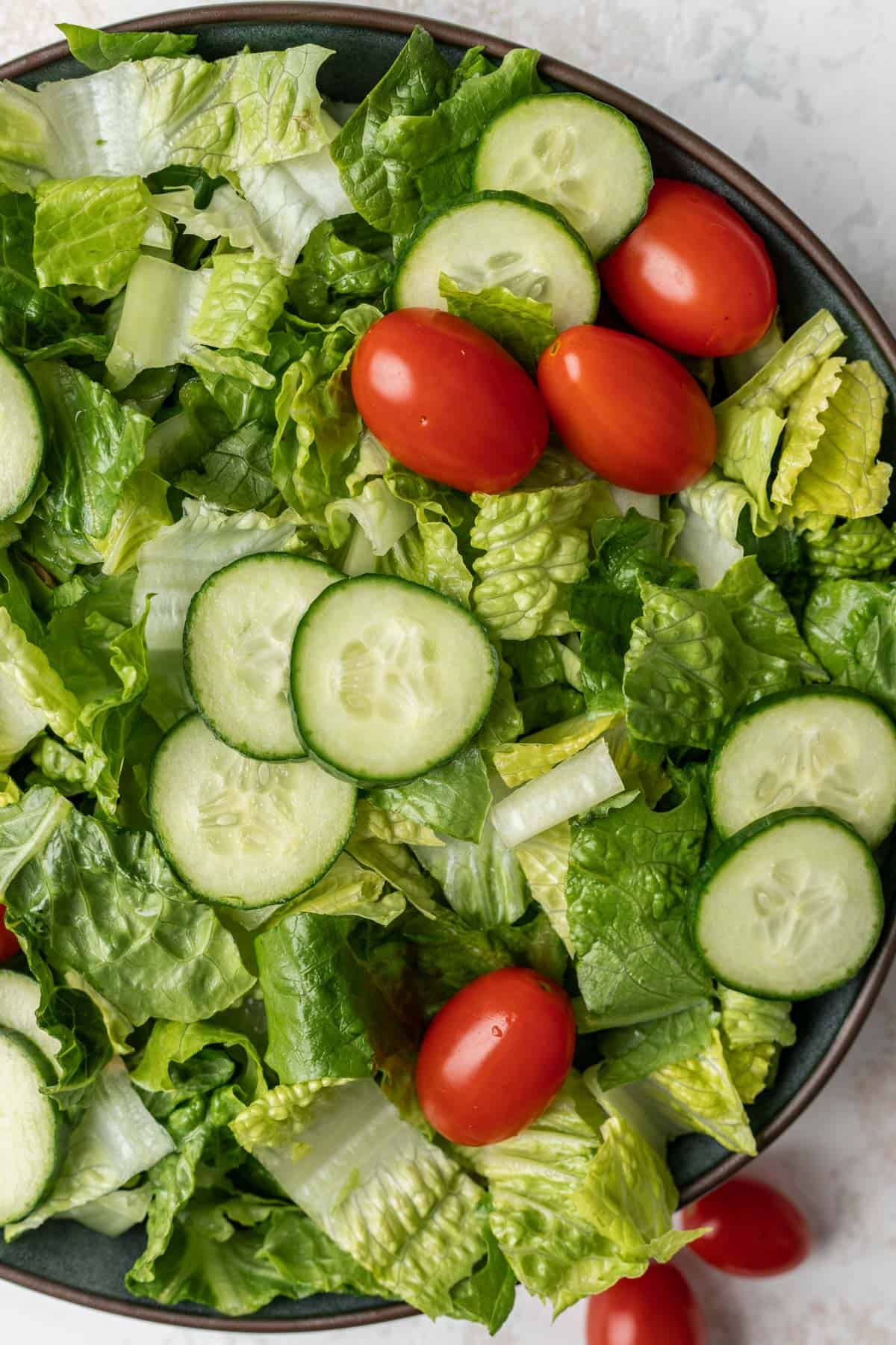 A salad made of romaine lettuce, cherry tomatoes, and cucumbers.