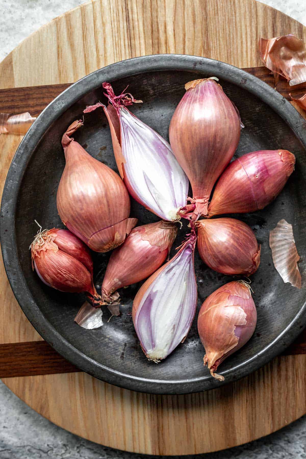 A bunch of shallots in a metal dish.