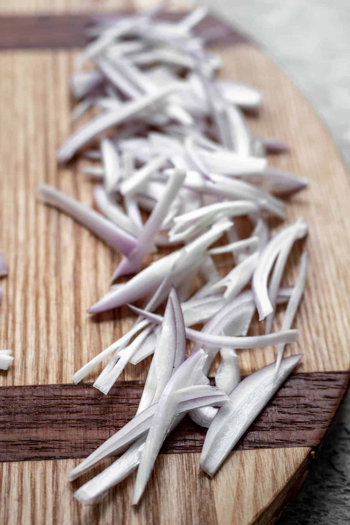 Julienned slices of shallot on a cutting board.