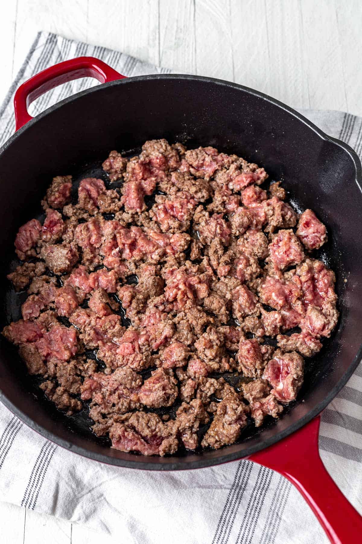 Seasoned raw ground beef in a skillet.