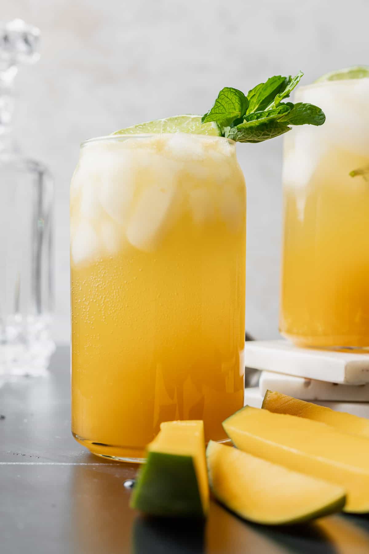 A mango mojito garnished with mint and surrounded by fresh mango slices.